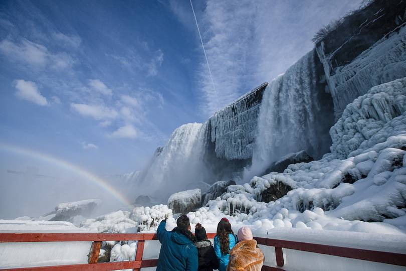 A family at the base of the falls in winter at Niagara Falls State Park